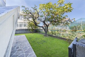 Une cour intérieure avec un arbre, un chemin en pierre et une vue sur un bâtiment doté d’une façade en verre.