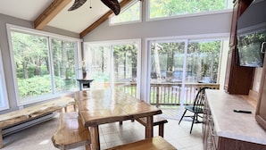 A spacious kitchen with a wooden table and benches, large windows, and a ceiling fan. - Lakefront Escape - Private Dock - Pet Friendly (Albrightsville)