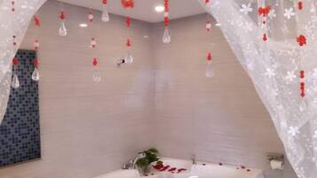A modern bathroom with a freestanding bathtub, a glass shower enclosure, and a tiled wall.