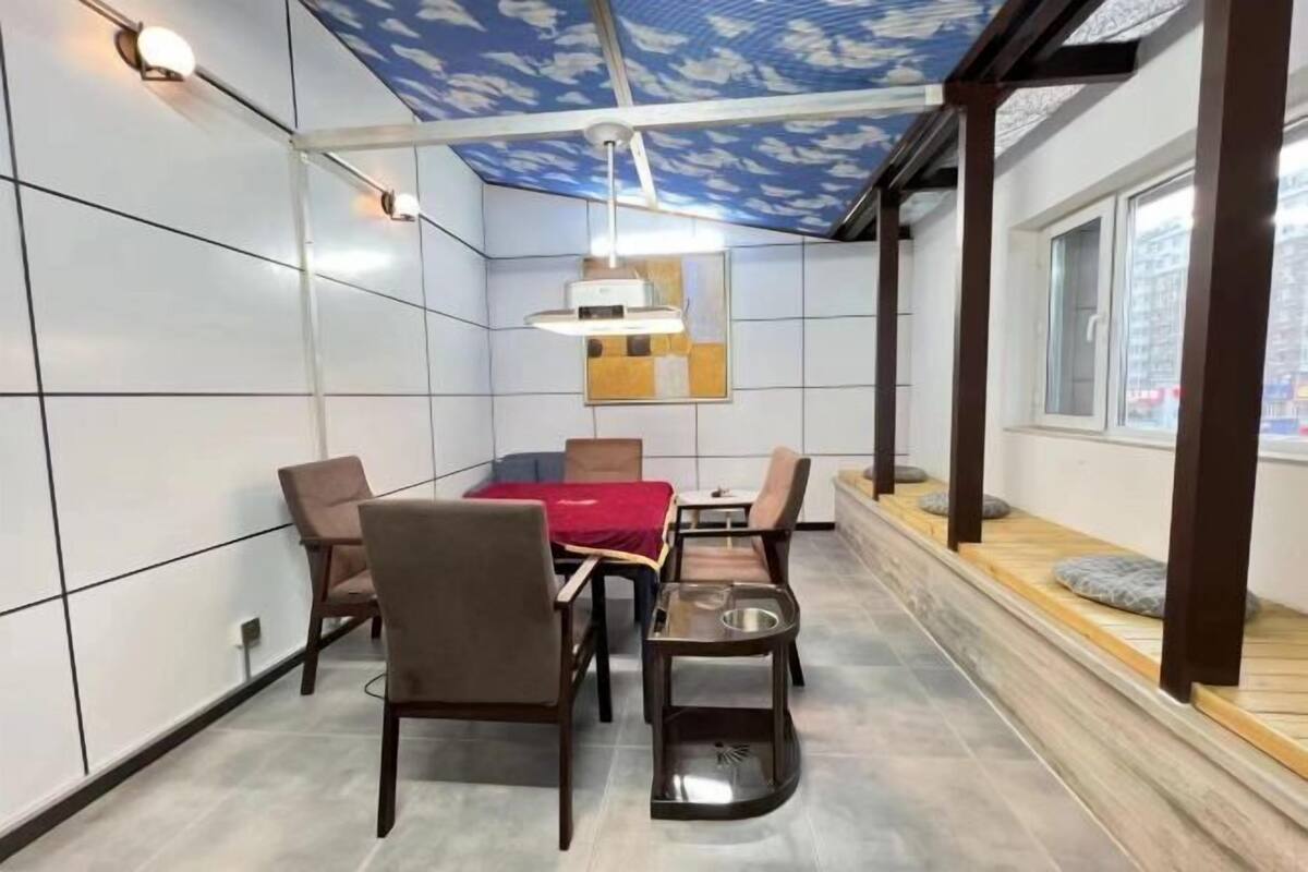 A modern dining area with a table and chairs, a ceiling with a blue pattern, and a window with a view.