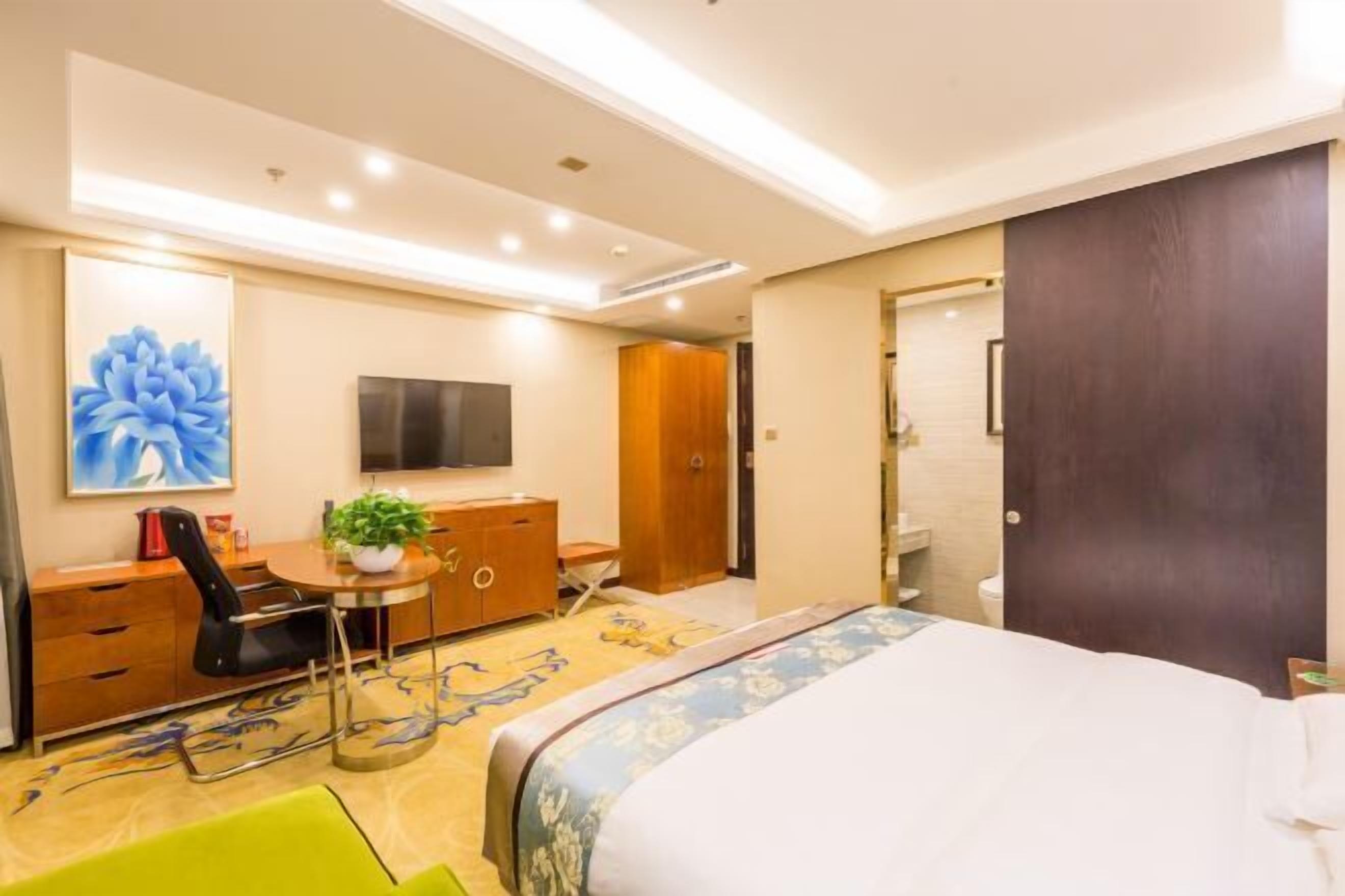 Een hotelkamer met een bed, een bureau met stoel, een televisie, een kledingkast en een badkamer.