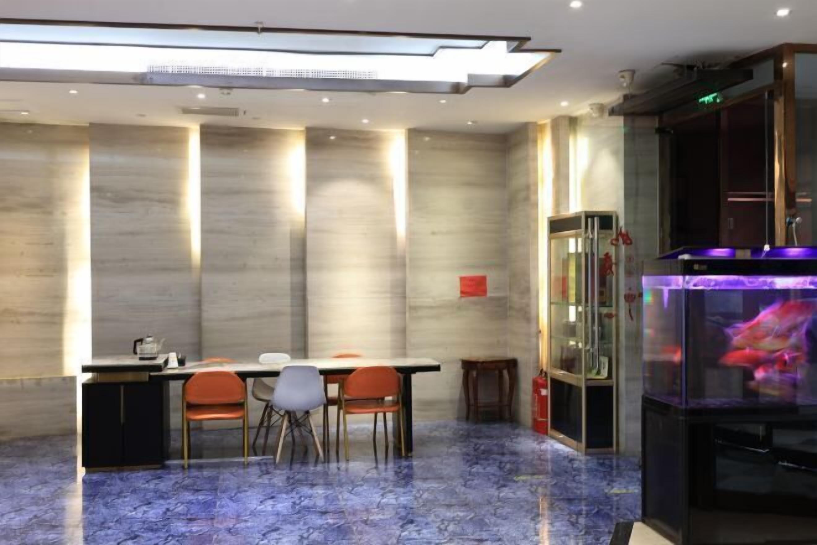 A modern dining area with a marble floor, a long table with chairs, and a fish tank with colorful fish.
