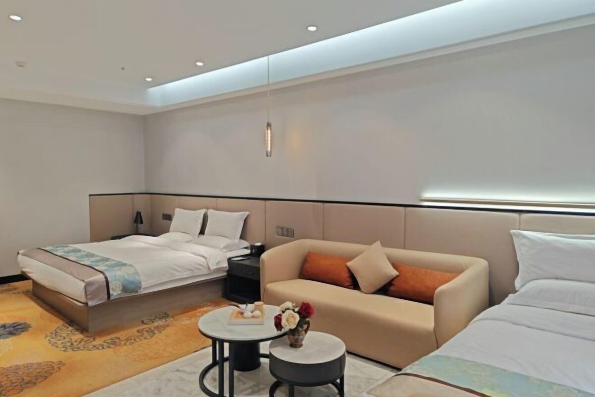 A hotel room with a bed, a sofa, a small table, and a nightstand.