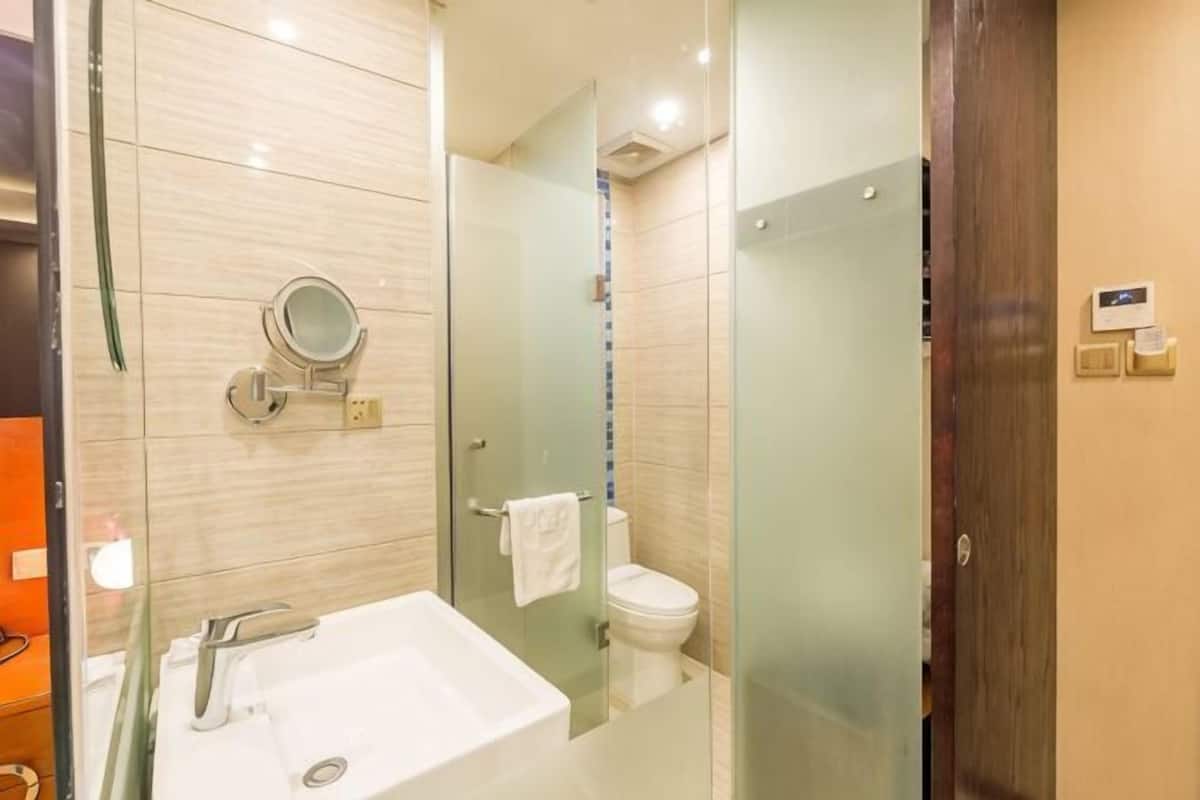 A modern bathroom with a glass shower enclosure, a white sink, and a toilet.
