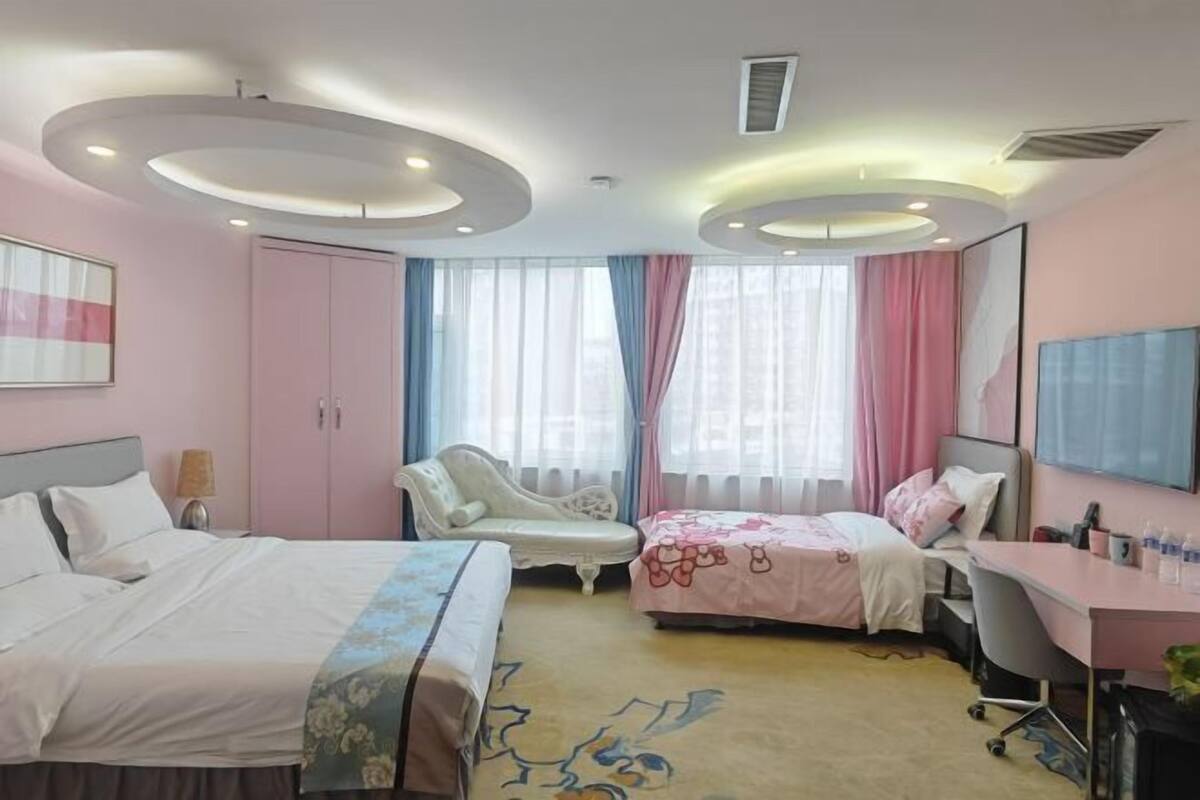 A bedroom with two beds, a desk, a chair, a wardrobe, and a large mirror.