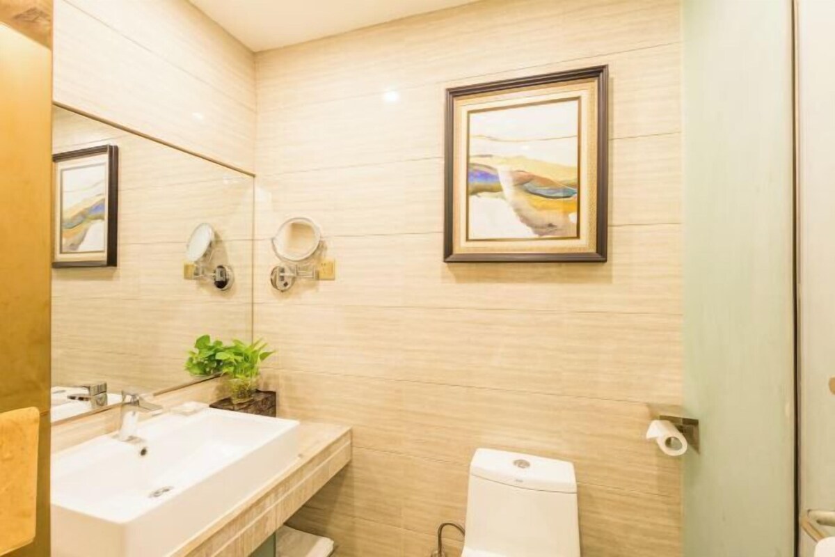 A bathroom with a sink, mirror, toilet, and framed artwork on the wall.