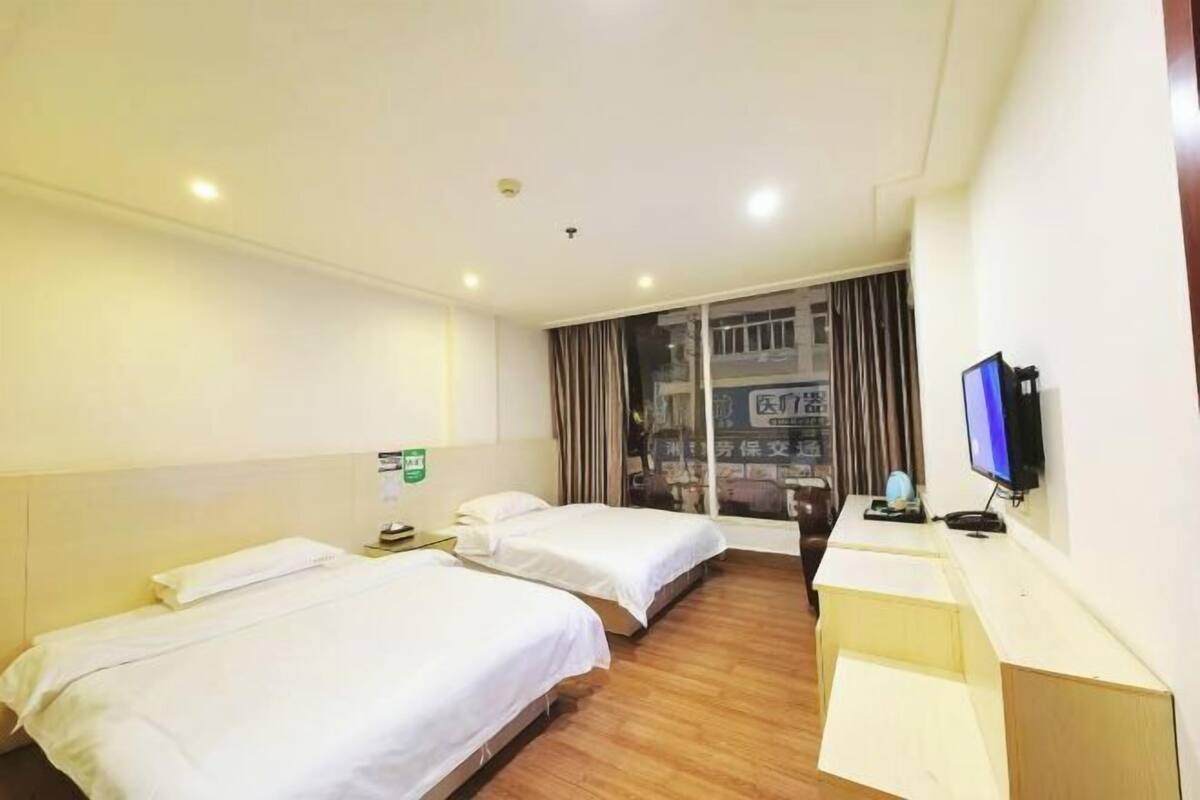 A hotel room with two beds, a desk with a computer, and a window with curtains.