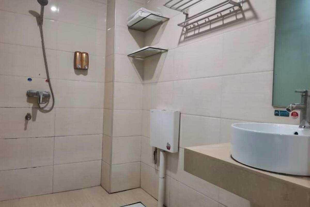 A bathroom with a shower, a sink, and a hand dryer.
