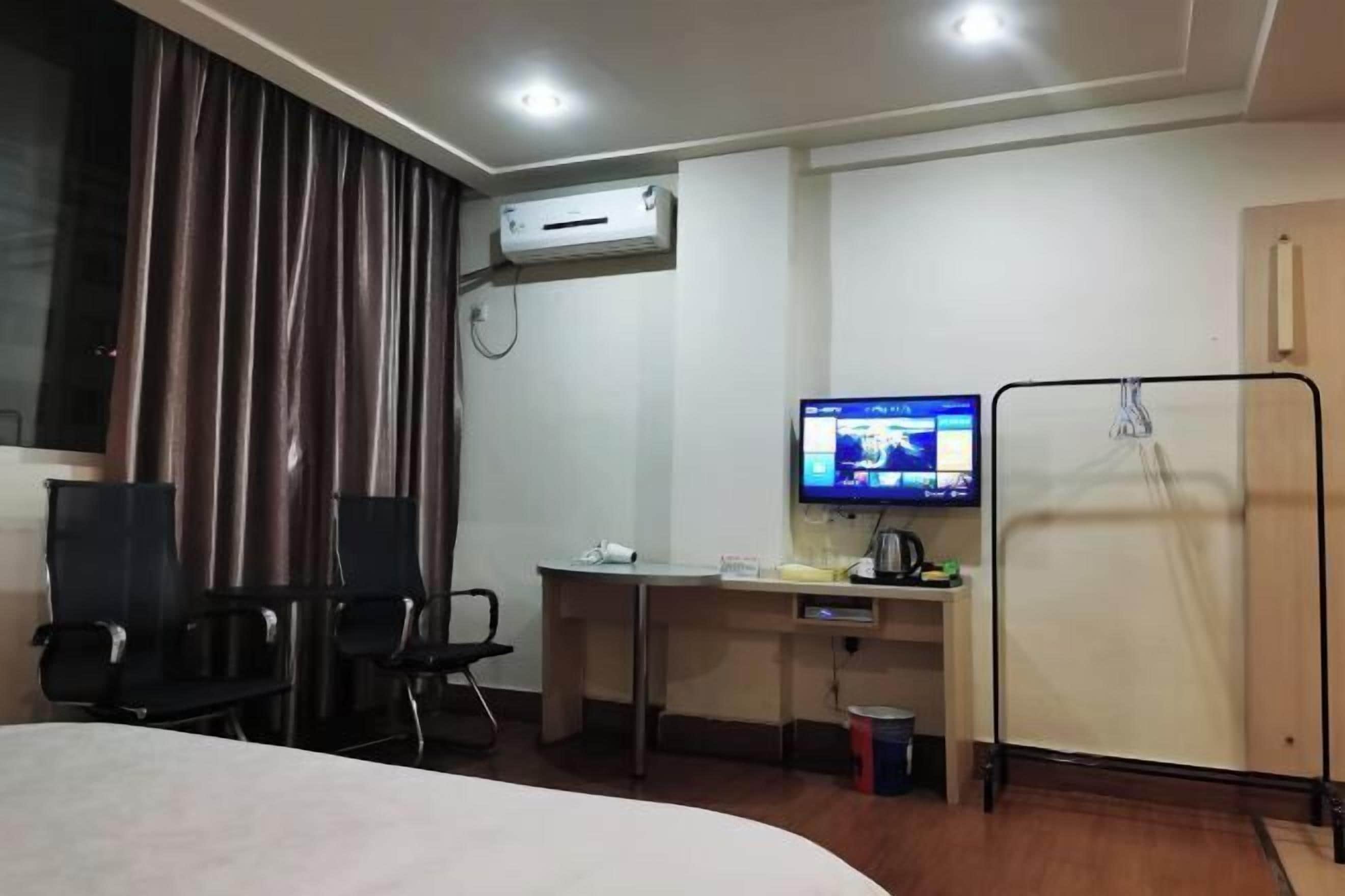 Une chambre d’hôtel équipée d’un lit, d’un bureau avec un ordinateur, d’une télévision et d’un appareil de climatisation.