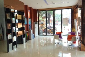 A modern lobby with a glass door leading outside, a reception desk, and colorful chairs. - Xinju Express Hotel (Hezhou)