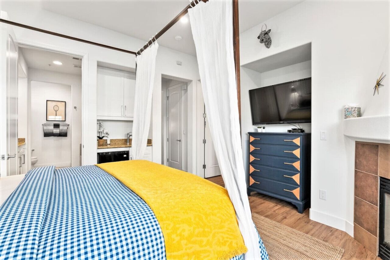 Une chambre à coucher avec un lit à baldaquin, une télévision, une commode et une cheminée.