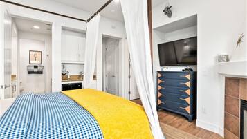 Une chambre à coucher avec un lit à baldaquin, une télévision, une commode et une cheminée.