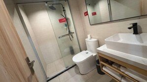 A modern bathroom with a glass-enclosed shower, a white sink, and a toilet. - Lihuang Hotel (Jiaxing)