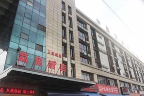 Fachada de hotel con grandes ventanales, señalización y varios pisos.