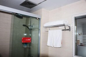 Ein Badezimmer mit Duschkabine aus Glas, einem Handtuchhalter mit einem weißen Handtuch und einem roten Feuerschutzschild.