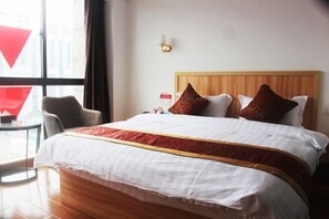 A hotel room with a large bed, a wooden headboard, and a small table with a chair. - Lihuang Hotel (Jiaxing)