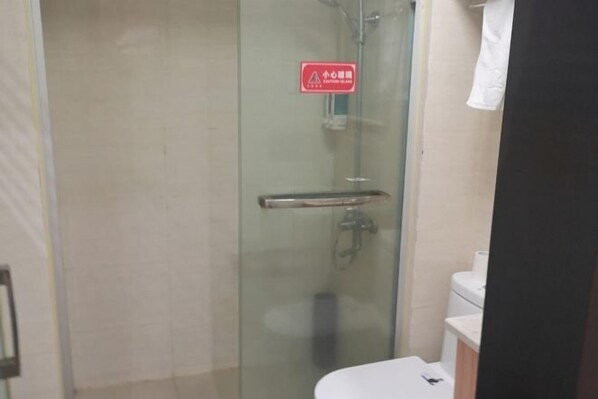 A glass-enclosed shower stall with a red safety sign, a white toilet, and a white sink. - Lihuang Hotel (Jiaxing)