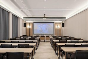 A conference room with rows of tables and chairs, a large screen at the front, and a projector. - Mingji Hotel (Guangzhou Shawan Old Town) (Guangzhou)