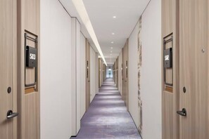 A hotel corridor with doors marked with room numbers, a patterned carpet, and a modern design. - Mingji Hotel (Guangzhou Shawan Old Town) (Guangzhou)