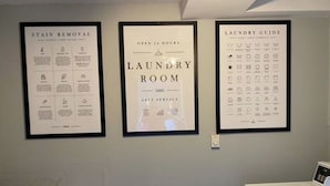 Un lavadero con zona de autoservicio, una guía para quitar manchas y un manual de lavandería en la pared.