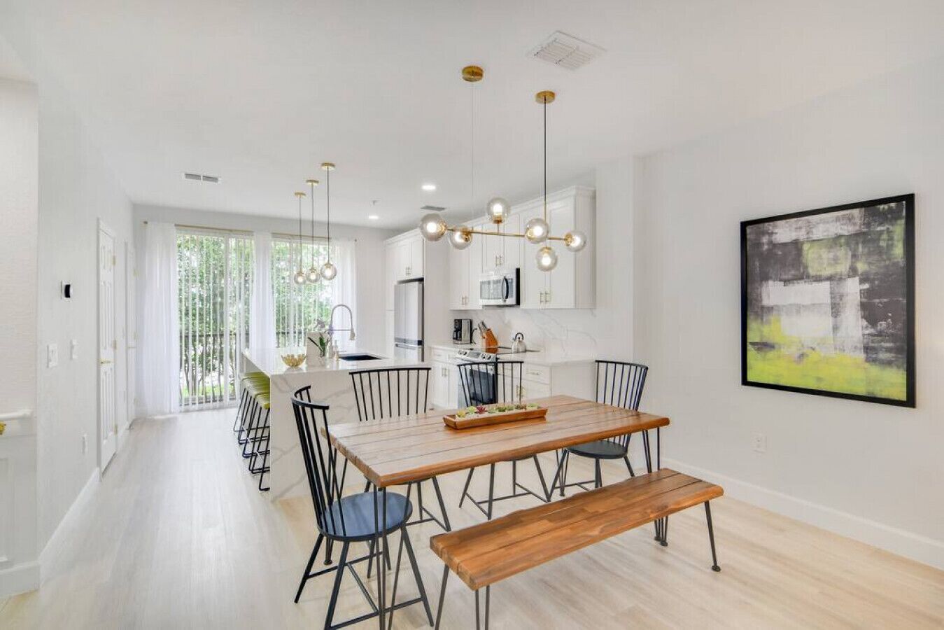 Une cuisine moderne avec des meubles blancs, un îlot central et des luminaires suspendus.