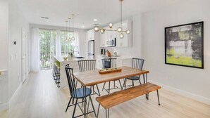 Una cocina moderna con armarios blancos, una isla central e iluminación colgante.