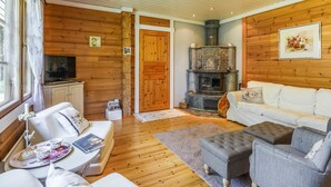 Interior acogedor de una cabaña con chimenea, paredes de madera, un sofá y un televisor.