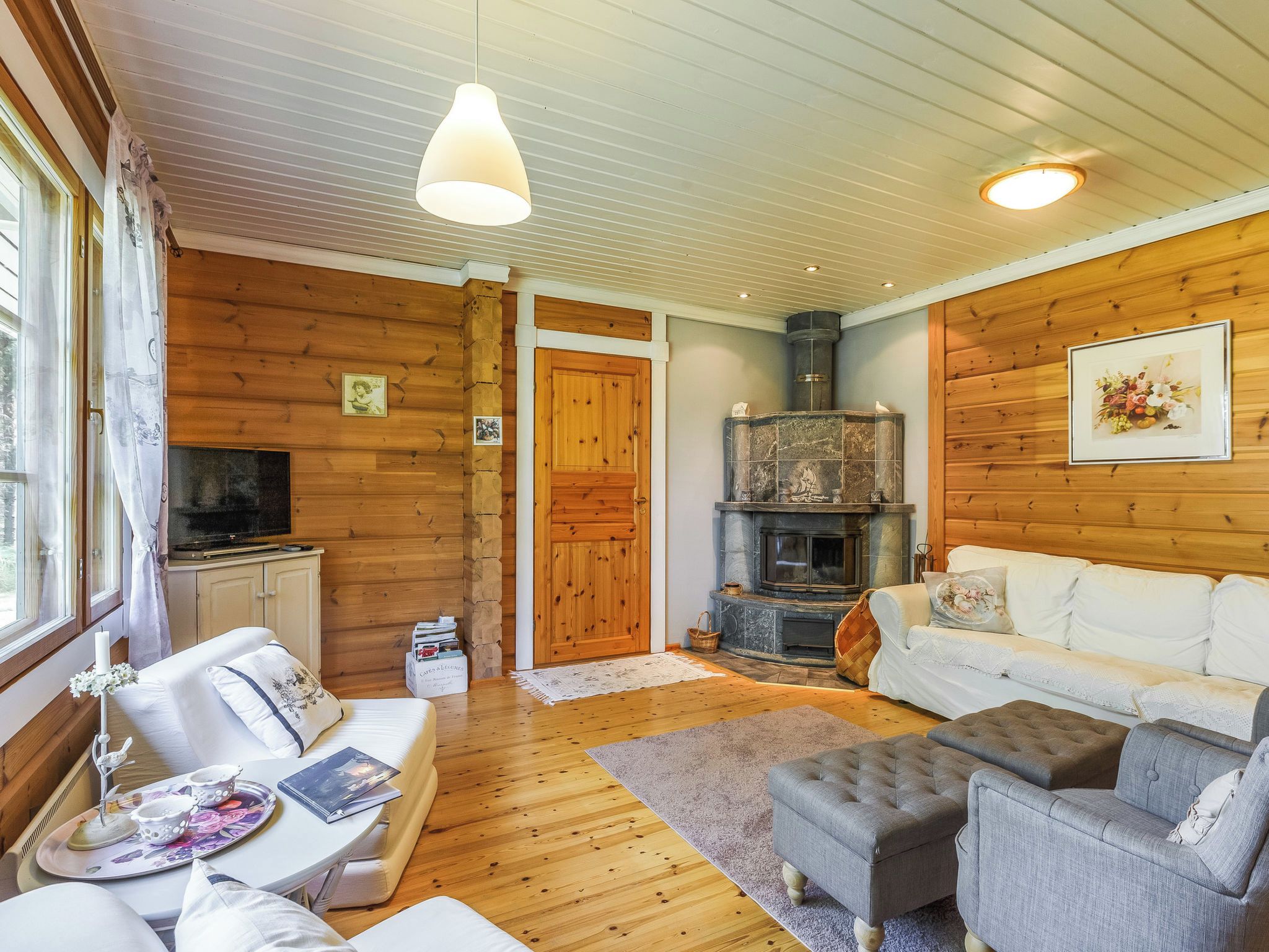 A cozy living room with a fireplace, wooden walls, and a comfortable seating area.