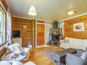 A cozy living room with a fireplace, wooden walls, and a comfortable seating area. - Kiviniemi by Interhome (Punkaharju)