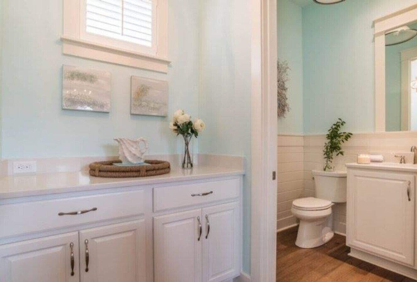 A bathroom with white cabinets, a toilet, and a sink area.