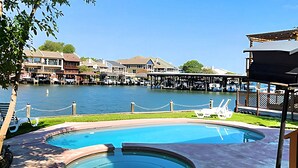 A swimming pool with a view of a waterfront and buildings in the background. - Lakefront Retreat with Pool, Spa, Golf, Fishing,  Boat slip, Kayaks & Marina (Montgomery)