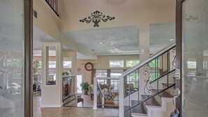 A spacious foyer with a grand staircase, a chandelier, and a view of the outdoors. - Lakefront Retreat with Pool, Spa, Golf, Fishing,  Boat slip, Kayaks & Marina (Montgomery)