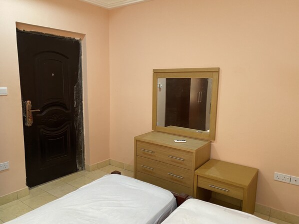 A bedroom with a bed, a dresser, a mirror, and a door.