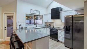 Una cocina moderna con una isla central, electrodomésticos de acero inoxidable y armarios blancos.