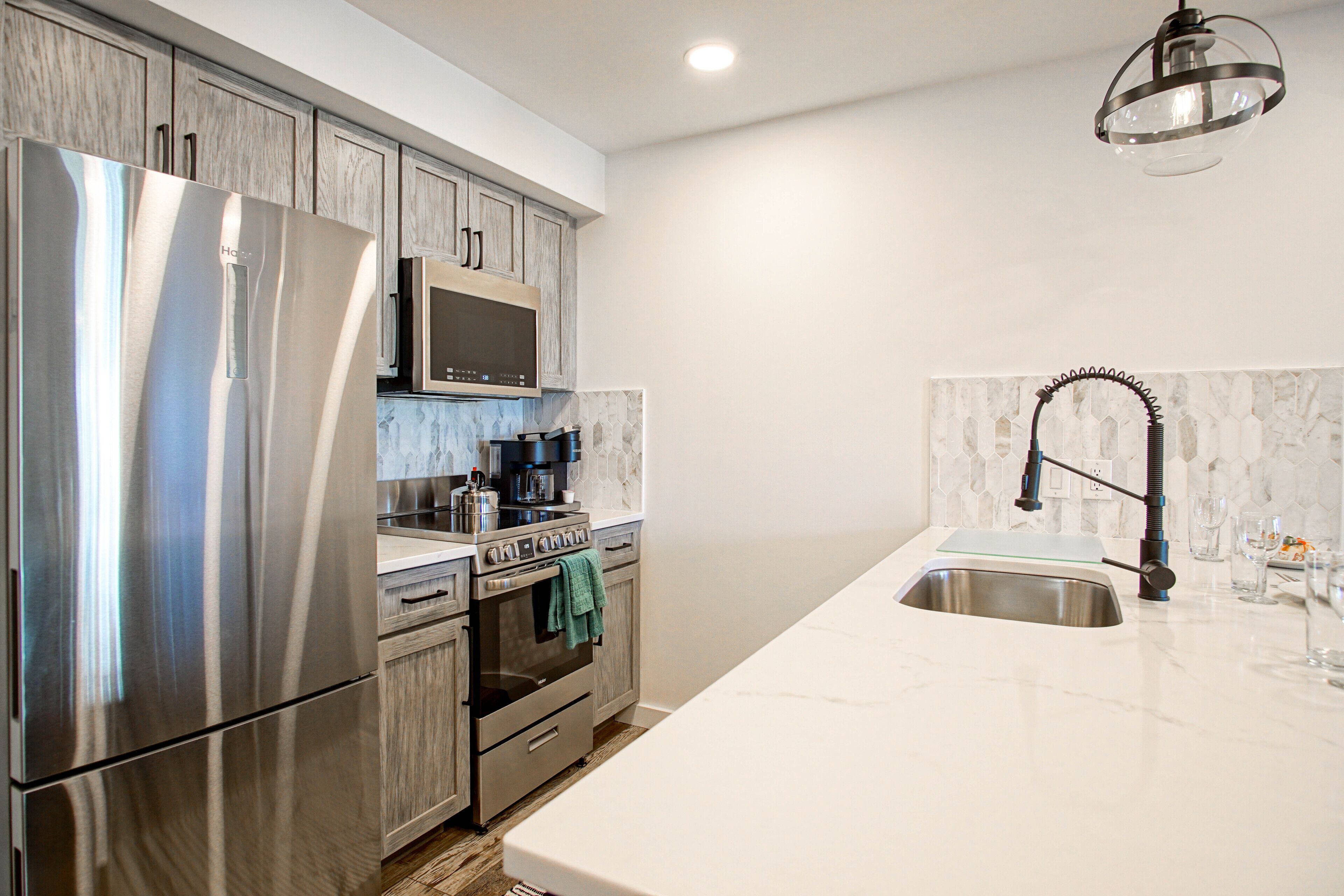 A modern kitchen with stainless steel appliances, a marble countertop, and a built-in oven.