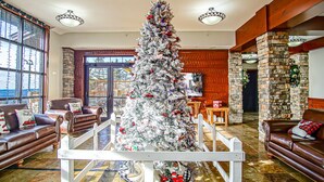 Um hall amplo com uma grande árvore de Natal, sofás de couro e uma parede de pedra.