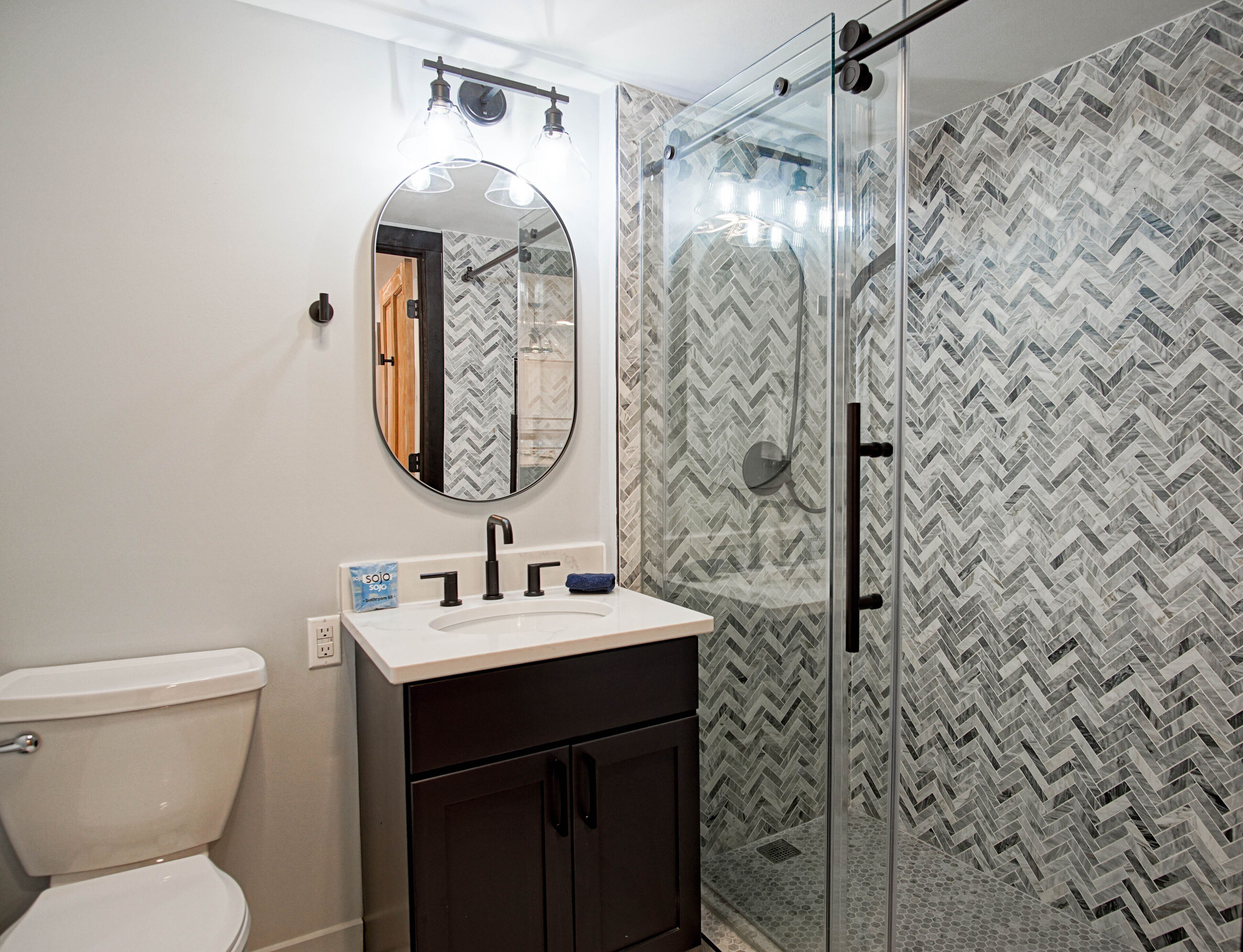 A bathroom with a toilet, a sink with a mirror above it, and a shower area with a glass door.