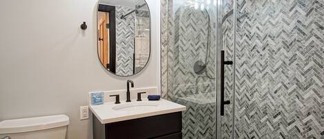 A bathroom with a toilet, a sink with a mirror above it, and a shower area with a glass door.
