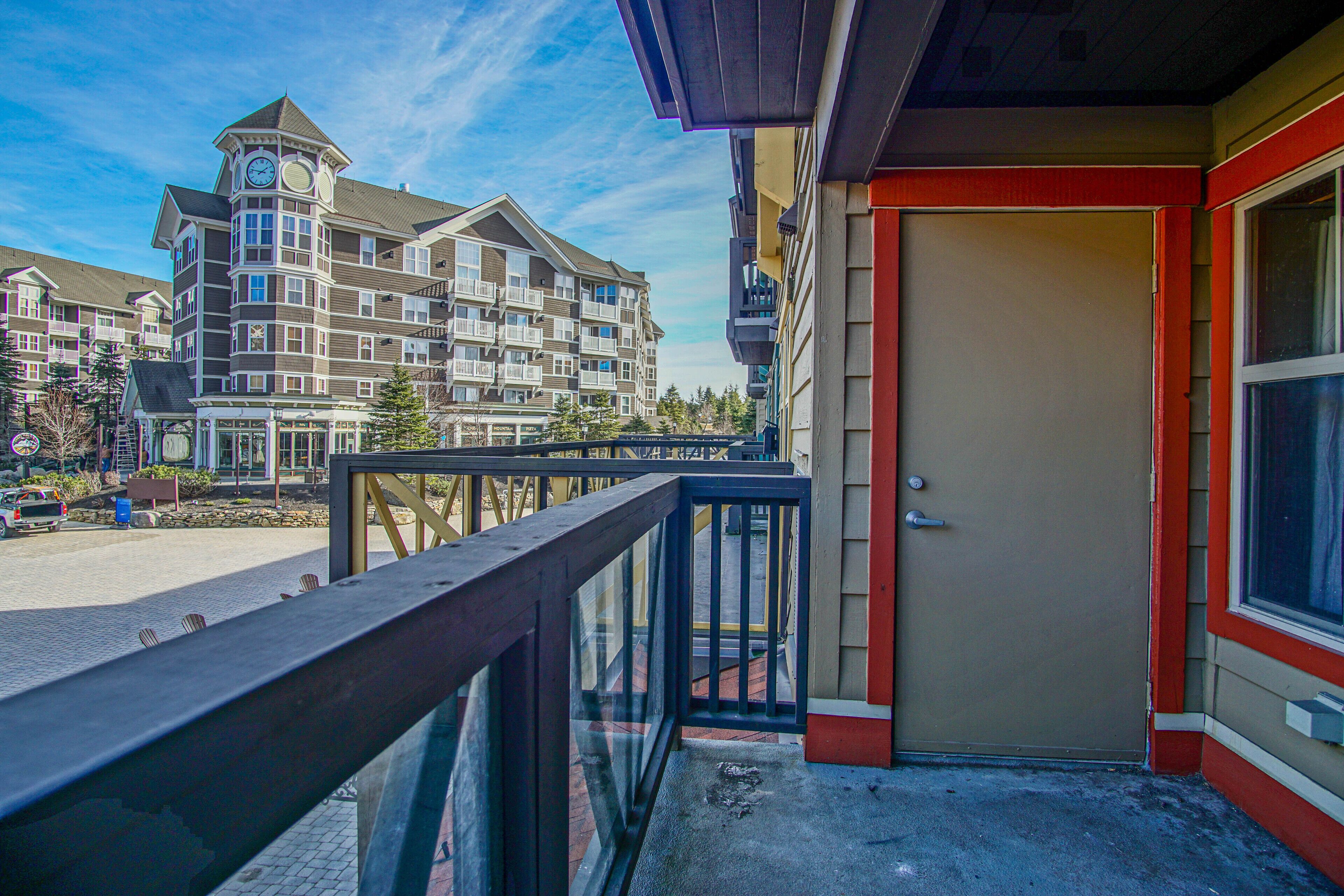 A hotel with a balcony, a door, and a view of other buildings.