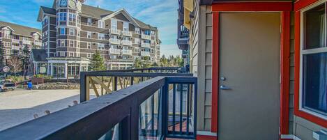A hotel with a balcony, a door, and a view of other buildings.