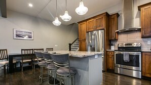 Une cuisine moderne dotée d’un îlot central, d’appareils électroménagers en acier inoxydable et de meubles de rangement en bois.