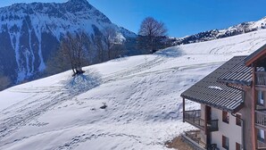 Eine verschneite Berglandschaft mit einer Holzhütte und einem Balkon.