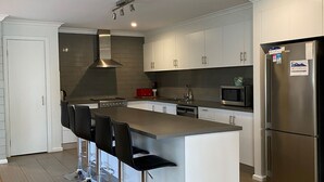 A modern kitchen with a central island, stainless steel appliances, and bar stools.