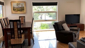 A living room with a dining area, a large window, a television, and a 'WHATEVER' sign on the wall.