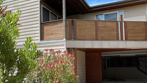 A two-story house with a balcony, a garage, and a garden with red flowers.