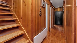 Interior de madeira com escada, radiador e porta que dá para outro cômodo.