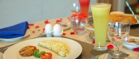 Une table dressée pour le petit-déjeuner, avec une omelette, des toasts et un verre de jus d’orange.