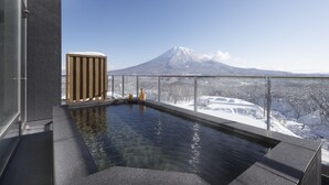 Un jacuzzi con vistas a un paisaje nevado y una montaña al fondo.