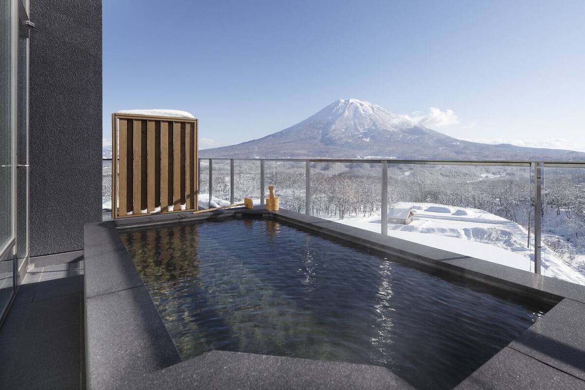 A hot tub with a view of a snow-covered landscape and a mountain in the distance.