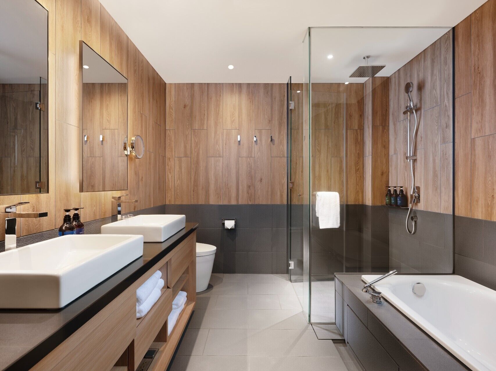 Un baño moderno con paneles de madera, cabina de ducha de vidrio y una bañera grande.